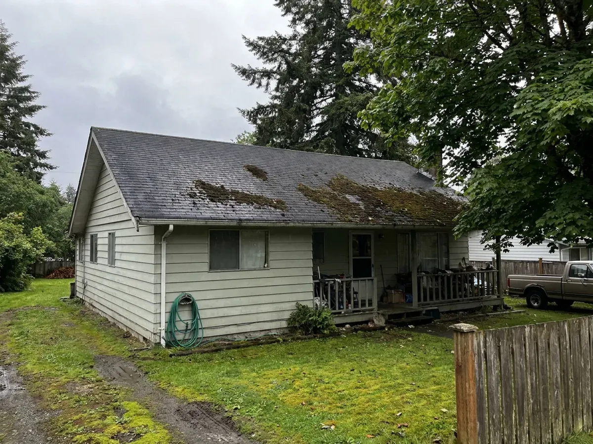 Moss cleared from the lower slope of a shingle roof on a shaded Cowichan Valley property